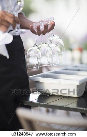 Close up of waiter with wine glasses between fingers in patio restaurant View Large Photo Image Stock Photo - Close up of waiter with wine glasses between fingers in patio restaurant. Fotosearch
