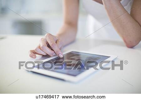 Close up of young womans hand using digital tablet touchscreen on kitchen counter View Large Photo Image Stock Photo - Close up of young womans hand using digital tablet touchscreen on kitchen counter. Fotosearch