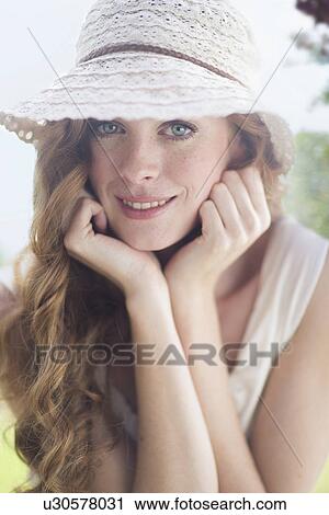 Stock Image - Close up portrait of beautiful young woman in garden. Fotosearch