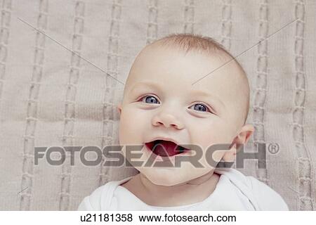 Stock Photo - Close up portrait of smiling baby boy lying on blanket. Fotosearch