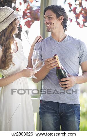 Stock Photograph - Couple chatting and laughing in garden wine bar. Fotosearch