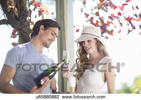 Stock Image - Couple drinking champagne in garden wine bar. Fotosearch