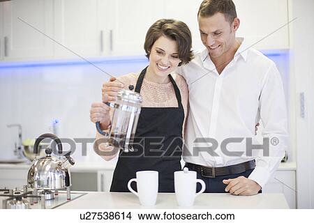Couple pouring a coffee from french press in kitchen View Large Photo Image Picture - Couple pouring a coffee from french press in kitchen. Fotosearch