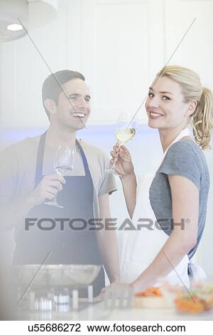 Couple preparing food and drinking glass of white wine in kitchen View Large Photo Image Stock Image - Couple preparing food and drinking glass of white wine in kitchen. Fotosearch