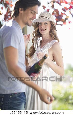 Stock Photography - Couple preparing to celebrate with champagne in garden wine bar. Fotosearch