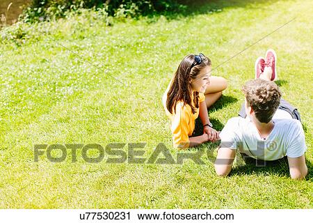 Couple sitting on grass in the park View Large Photo Image Stock Image - Couple sitting on grass in the park. Fotosearch