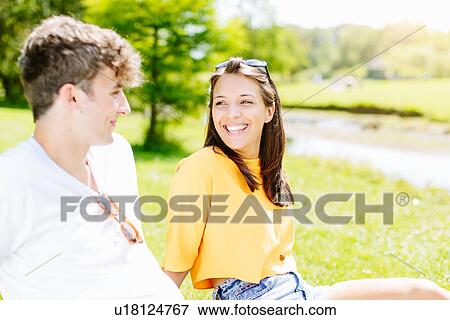 Stock Photo - Couple sitting on grass in the park. Fotosearch