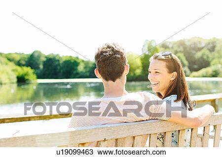 Couple sitting on wooden park bench View Large Photo Image Stock Image - Couple sitting on wooden park bench. Fotosearch