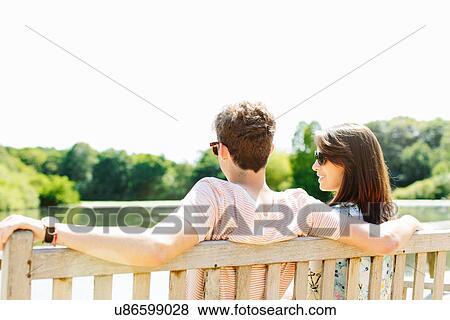 Stock Photo - Couple sitting on wooden park bench. Fotosearch