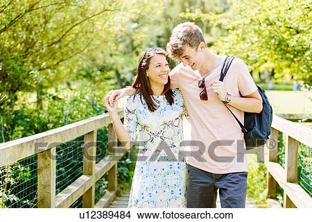 Picture - Couple walking over wooden bridge in the park. Fotosearch