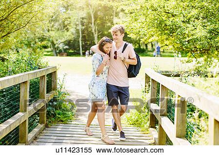Stock Photography - Couple walking over wooden bridge in the park. Fotosearch