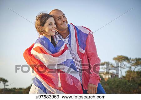 Stock Photo - Couple wrapped in british flag on Bournemouth beach, Dorset, UK. Fotosearch