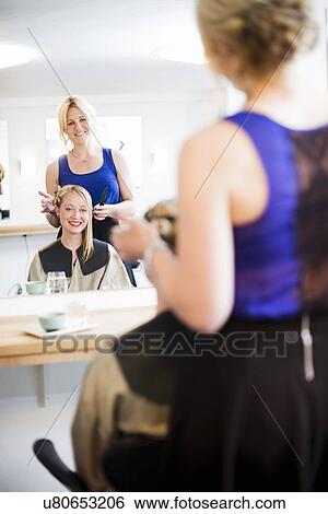 Stock Photograph - Customer and hairdresser reflected in mirror. Fotosearch
