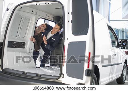 Customer and salesman checking vehicle interior in car dealership View Large Photo Image Stock Photo - Customer and salesman checking vehicle interior in car dealership. Fotosearch