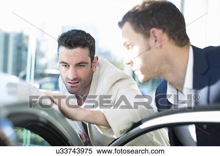 Customer looking at car roof in car dealership View Large Photo Image Stock Photography - Customer looking at car roof in car dealership. Fotosearch