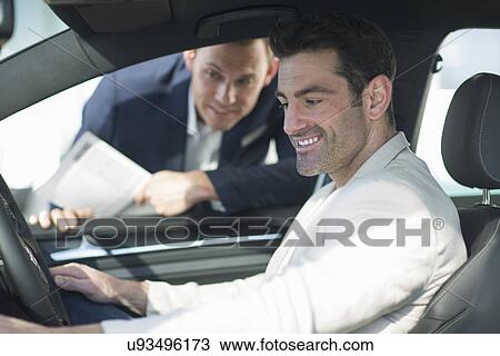 Stock Image - Customer trying out new car in car dealership. Fotosearch