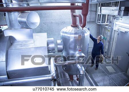 Stock Photography - Elevated view of engineer inspecting machinery in power station. Fotosearch