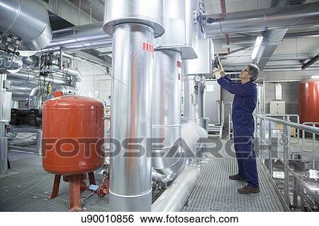 Stock Photograph - Engineer adjusting equipment in power station. Fotosearch