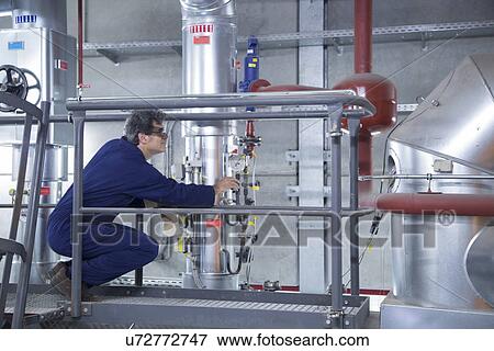 Stock Photo - Engineer inspecting equipment from access platform in power station. Fotosearch