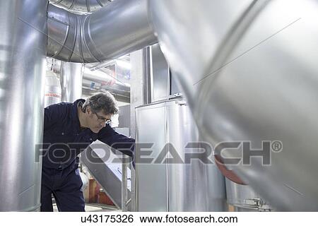 Engineer inspecting industrial piping in power station View Large Photo Image Stock Photograph - Engineer inspecting industrial piping in power station. Fotosearch