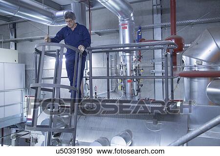 Stock Image - Engineer inspecting on stairs of access platform in power station. Fotosearch