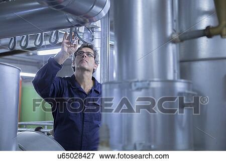 Engineer inspecting pipes in power station View Large Photo Image Stock Photo - Engineer inspecting pipes in power station. Fotosearch