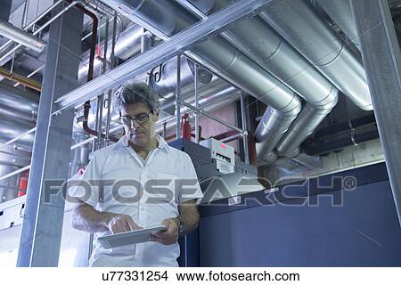 Engineer using touchscreen on digital tablet in power station View Large Photo Image Picture - Engineer using touchscreen on digital tablet in power station. Fotosearch