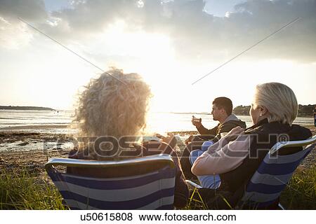 Stock Photo - Family members relaxing by beach. Fotosearch