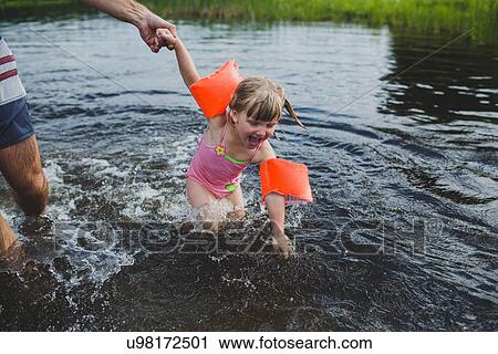 Stock Image - Father and daughter wading and splashing in Indian river, Ontario, Canada. Fotosearch