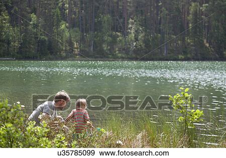 Father and son looking down into lake, Somerniemi, Finland View Large Photo Image Stock Photo - Father and son looking down into lake, Somerniemi, Finland. Fotosearch