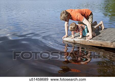 Father and son looking down into lake from pier, Somerniemi, Finland View Large Photo Image Stock Photo - Father and son looking down into lake from pier, Somerniemi, Finland. Fotosearch