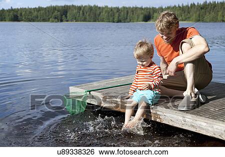 Father and son sitting on lake pier, Somerniemi, Finland View Large Photo Image Stock Photograph - Father and son sitting on lake pier, Somerniemi, Finland. Fotosearch