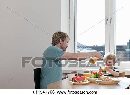 Father and toddler son having breakfast at kitchen table View Large Photo Image Stock Photograph - Father and toddler son having breakfast at kitchen table. Fotosearch