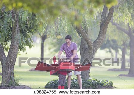Stock Photography - Father preparing toy airplane for his son in park. Fotosearch