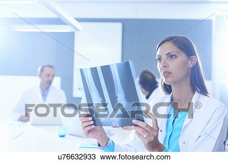 Stock Image - Female doctor looking at x-ray. Fotosearch