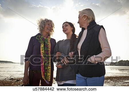 Stock Image - Female family members chatting on beach. Fotosearch