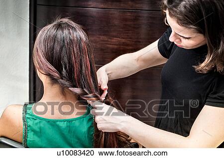 Female hairdresser braiding young woman's long hair in hair salon View Large Photo Image Stock Image - Female hairdresser braiding young woman's long hair in hair salon. Fotosearch