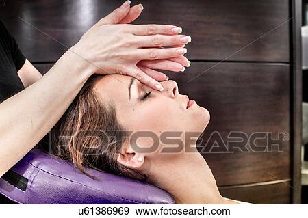 Stock Photo - Female masseur massaging young woman's face in beauty salon. Fotosearch