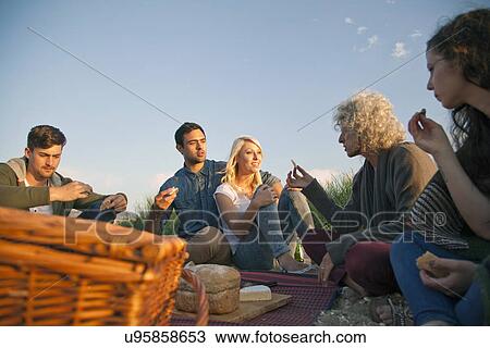 Stock Image - Five adult friends having picnic on Bournemouth beach, Dorset, UK. Fotosearch