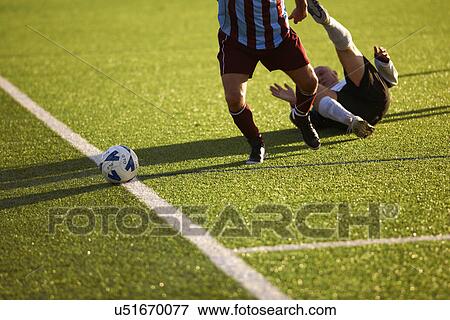 Stock Photo - Football players down on ground during game. Fotosearch
