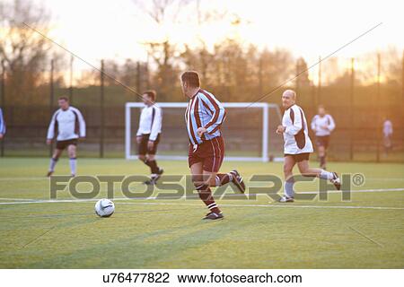 Stock Image - Football players running after ball. Fotosearch