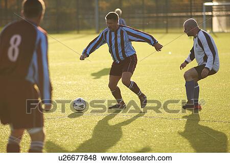 Football players running after ball View Large Photo Image Stock Photo - Football players running after ball. Fotosearch
