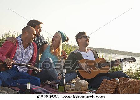 Stock Photo - Four adult friends having a party on Bournemouth beach, Dorset, UK. Fotosearch