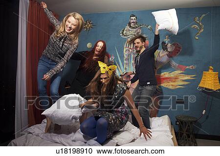 Four adult friends having pillow fight on hotel bed View Large Photo Image Stock Image - Four adult friends having pillow fight on hotel bed. Fotosearch