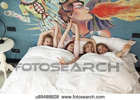 Four young women friends waking up in hotel bed View Large Photo Image Stock Photo - Four young women friends waking up in hotel bed. Fotosearch
