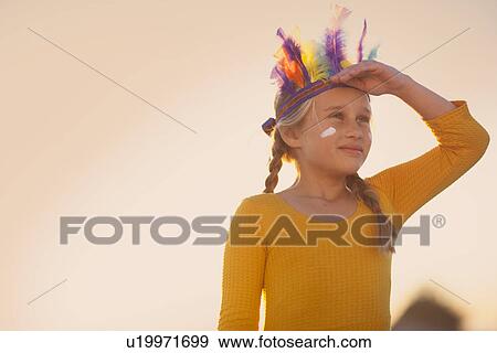 Girl dressed as native american in feather headdress with hand shading eyes View Large Photo Image Stock Photo - Girl dressed as native american in feather headdress with hand shading eyes. Fotosearch
