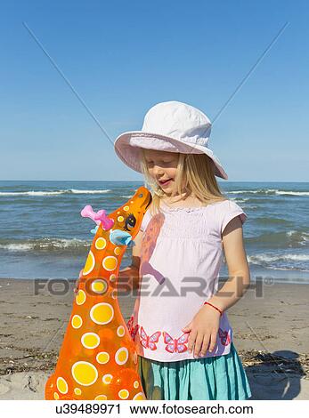 Stock Image - Girl holding up inflatable giraffe, Caleri Beach, Veneto, Italy. Fotosearch
