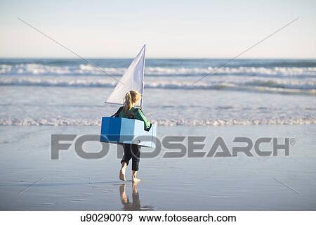 Stock Photo - Girl running with toy boat into sea. Fotosearch