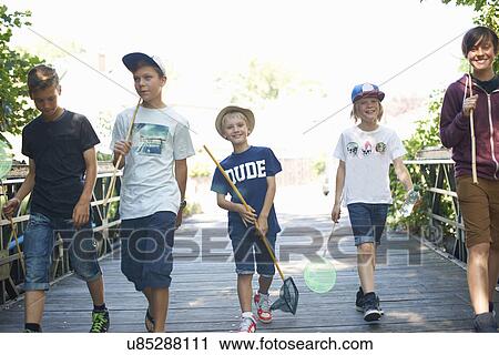 Stock Image - Group of boys on bridge with fishing nets. Fotosearch