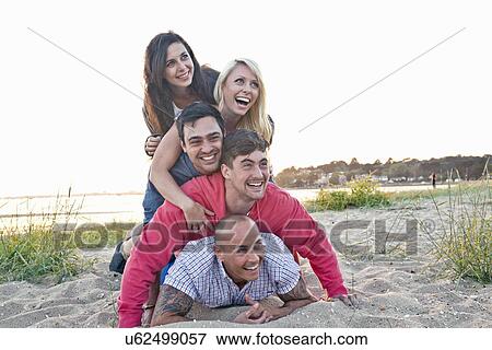 Group of friends making human pile on beach View Large Photo Image Stock Photo - Group of friends making human pile on beach. Fotosearch